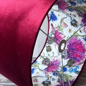 May include: A burgundy velvet lampshade with a white floral print lining. The print features purple and blue wildflowers.