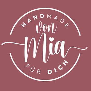 Puede incluir: Logotipo circular burdeos con la inscripción blanca "HANDMADE von Mia FÜR DICH". La palabra "Mia" está escrita en una fuente estilizada, con un pequeño corazón encima de la "i".