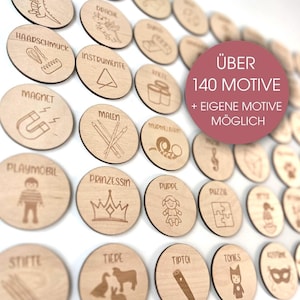 Puede incluir: Una colección de discos de madera con ilustraciones y texto grabados. Los discos presentan varias imágenes, incluyendo una corona, una muñeca y un imán. El texto en los discos incluye palabras como "Magnet" y "Princess". Un círculo rosa en la imagen dice "ÜBER 140 MOTIVE + EIGENE MOTIVE MÖGLICH".