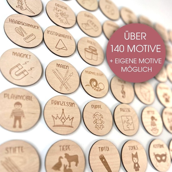 May include: A selection of wooden discs, each engraved with a different image and text. The discs display illustrations such as a crown, a doll, and a magnet. Text on the discs includes words like "Magnet" and "Princess". A pink circle in the image says "ÜBER 140 MOTIVE + EIGENE MOTIVE MÖGLICH".