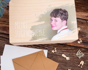 May include: A wooden box with a light wood finish. The box has a photo of a young person on the lid with the text "Meine Jugendweihe 12.01.2025".