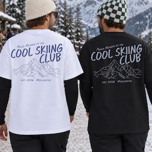 Pode incluir: Uma t-shirt branca e uma t-shirt preta, ambas com o texto "PROUD MEMBER OF THE COOL SKIING CLUB", um desenho de linha de montanha, "EST. 2026" e "#ZILLERTAL" nas costas. A t-shirt branca tem texto azul escuro, a preta texto branco.