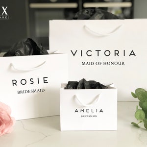 May include: Three white gift bags with black text. The bags are labeled "Rosie Bridesmaid", "Amelia Bridesmaid", and "Victoria Maid of Honour".