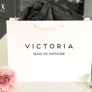 May include: White gift bag with black text that reads "VICTORIA MAID OF HONOUR".