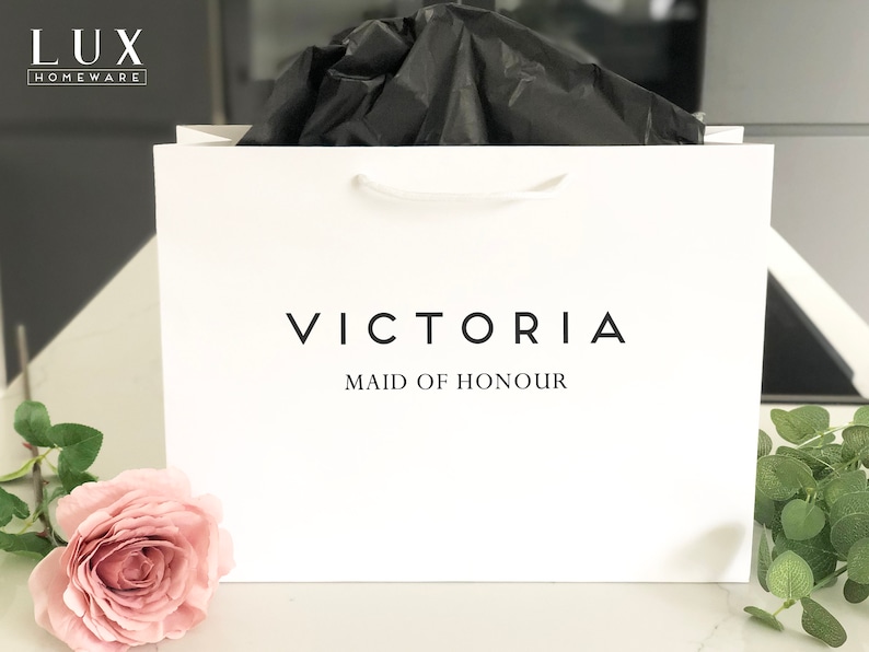 May include: White gift bag with black text that reads "VICTORIA MAID OF HONOUR".