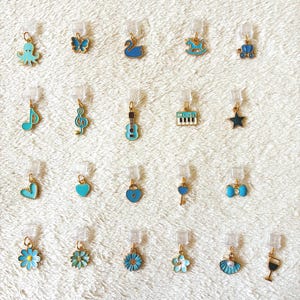 May include: A collection of small, colorful charms with gold-colored accents. The charms include an octopus, butterfly, swan, rocking horse, musical notes, a guitar, a piano, a star, hearts, flowers, a key, a bow, a seashell, and a wine glass.