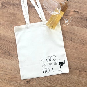 Könnte beinhalten: Weiße Stofftasche mit schwarzem Text "Zu Vino Sag Ich Nie No!" und einer schwarzen Silhouette eines Weinglases.