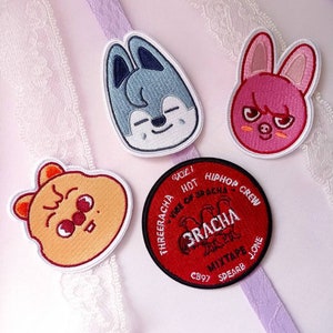 May include: Four embroidered patches with cartoon animal designs and text. The patches include a blue wolf, a pink bunny, an orange bear, and a red circular patch with the text "3RACHA MIXTAPE".