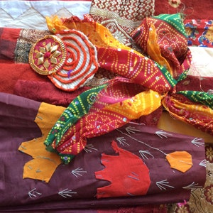 May include: A collection of colorful fabric scraps, including red, orange, yellow, green, and blue. The fabrics are arranged in a random pattern and some have intricate designs.