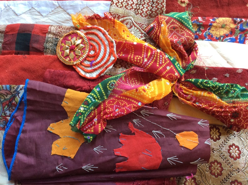 May include: A collection of colorful fabric scraps, including red, orange, yellow, green, and blue. The fabrics are arranged in a random pattern and some have intricate designs.