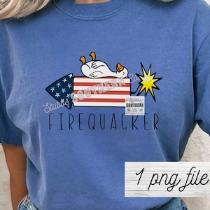 May include: Blue t-shirt featuring a cartoon goose on a firecracker with the text "FIREQUACKER". The firecracker has a red and white striped body and a blue triangle with stars. A yellow starburst is also present.