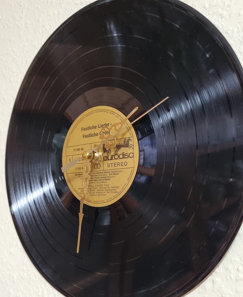 May include: A black vinyl record clock with gold hands and a gold label. The label has the text "Festliche Lieder - Festliche Ch&ouml;re" and "eurodisc STEREO".