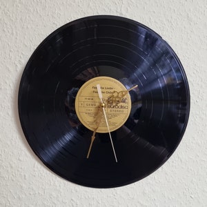 May include: A black vinyl record clock with gold hands. The record label is visible and reads "Festival der Lieder - Festival der Ch&ouml;re" with the text "Eurodisc Stereo" at the bottom.
