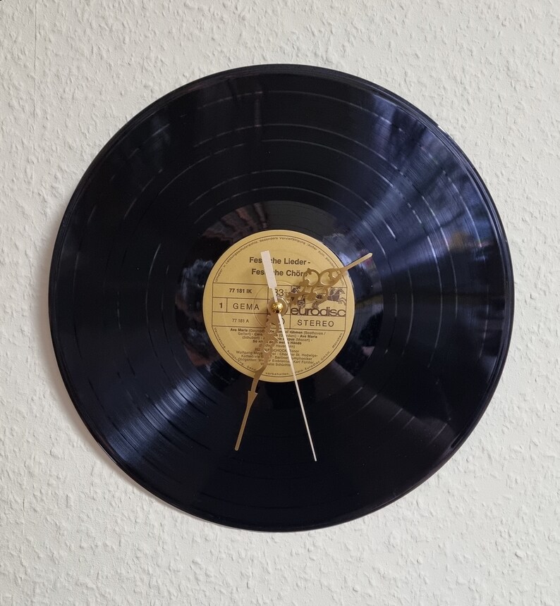 May include: A black vinyl record clock with gold hands. The record label is visible and reads "Festival der Lieder - Festival der Ch&ouml;re" with the text "Eurodisc Stereo" at the bottom.