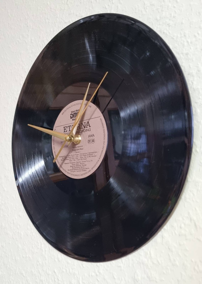 May include: A black vinyl record clock with gold hands. The record label is visible and reads "Eterna Recording AWA ST 33".