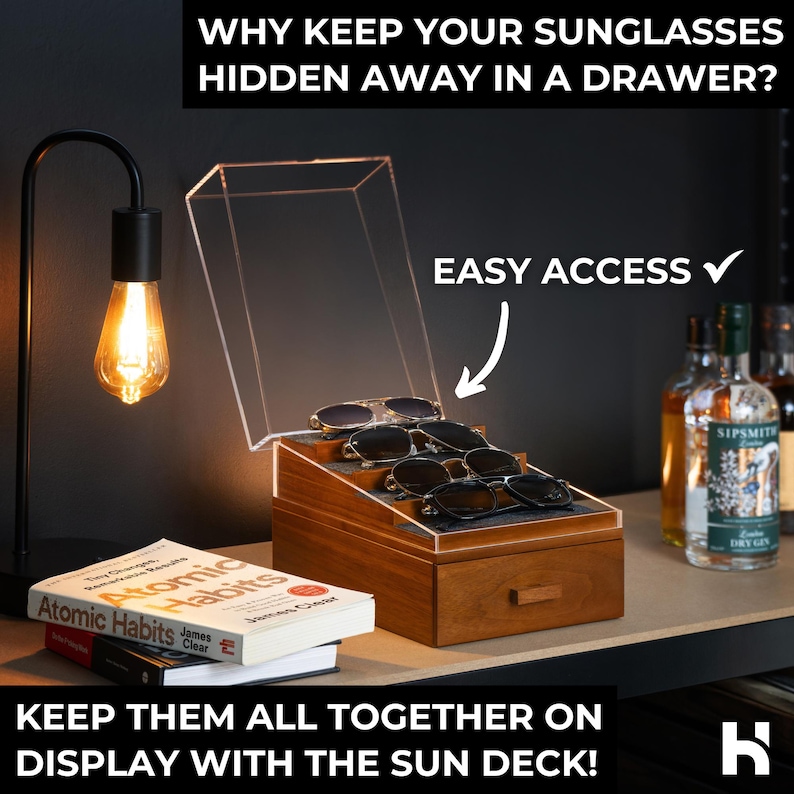 May include: A wooden sunglasses display case with a clear acrylic lid and a tiered interior holding four pairs of sunglasses. The case features a pull-out drawer and text that reads: WHY KEEP YOUR SUNGLASSES HIDDEN AWAY IN A DRAWER? EASY ACCESS. KEEP THEM ALL TOGETHER ON DISPLAY WITH THE SUN DECK!