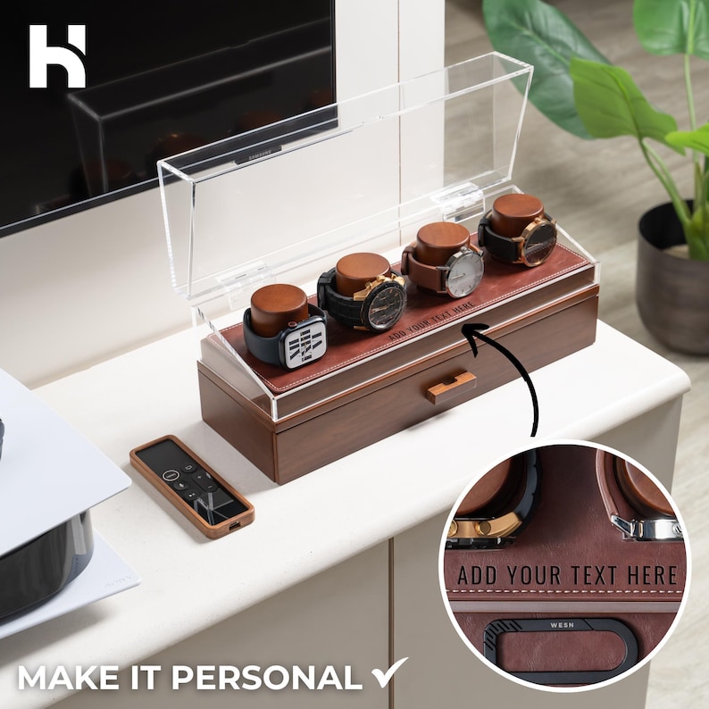 May include: A wooden watch display case with a clear acrylic lid, holding four watches with brown leather straps. The case has a brown leather interior and a small drawer. Text on the case reads "ADD YOUR TEXT HERE" and "MAKE IT PERSONAL".