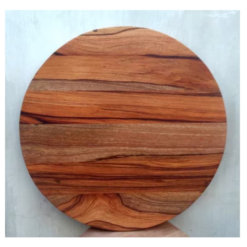 Puede incluir: Una tabla de cortar redonda de madera con un acabado de madera natural. La tabla tiene un color marr&oacute;n intenso con vetas marrones m&aacute;s oscuras en toda la veta.