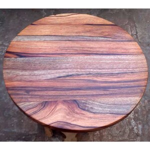 Puede incluir: Una tapa de mesa redonda de madera con un patr&oacute;n de veta de madera natural. La madera es de un color marr&oacute;n intenso con vetas m&aacute;s oscuras.