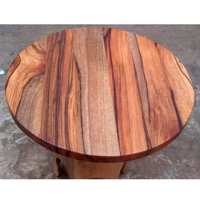 Puede incluir: Tapa redonda de mesa de madera con un patr&oacute;n de veta de madera natural. La madera es de un color marr&oacute;n rojizo intenso con vetas m&aacute;s oscuras en todo.