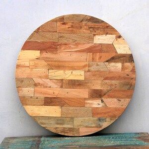 May include: A round wooden table top made from reclaimed wood. The surface is constructed from various rectangular pieces of wood in shades of brown and tan, arranged in a mosaic pattern. The table top has a diameter of approximately 30 inches.