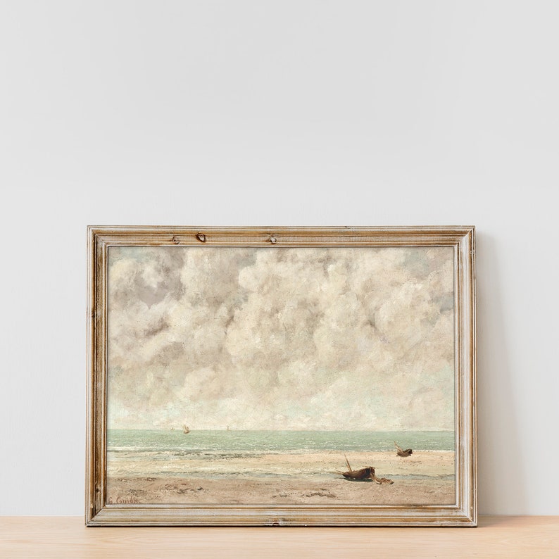 May include: A framed painting of a seascape with a cloudy sky and a sandy beach with two boats in the distance.