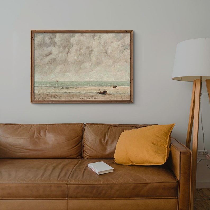 May include: A framed painting of a seascape with a cloudy sky and a beach with two boats in the distance.