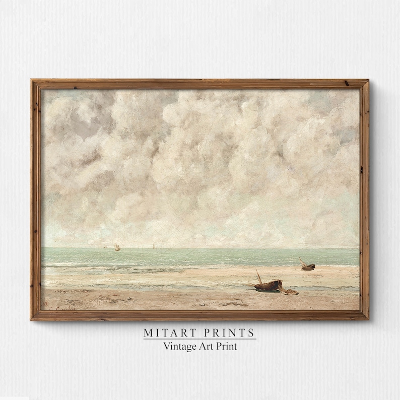 May include: A vintage art print of a seascape with a cloudy sky and two boats on the beach. The print is framed in a wooden frame.