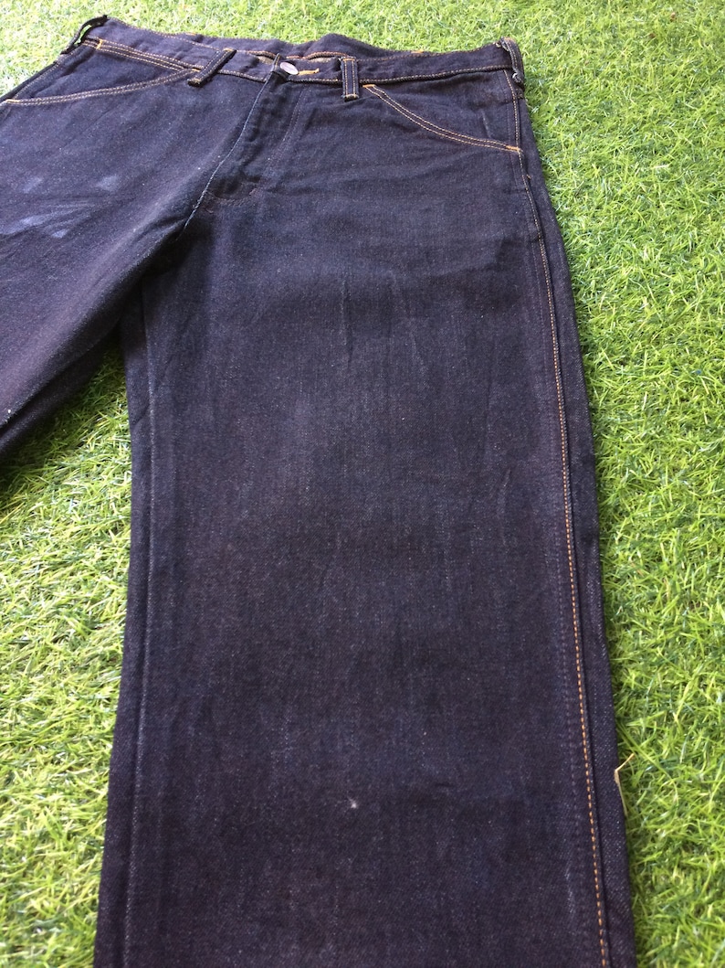Peut inclure: Un jean bleu fonc&eacute; &agrave; jambe droite avec des coutures jaunes le long des coutures.