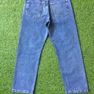 May include: A pair of blue denim jeans with a brown leather patch on the back pocket that says "Wrangler".