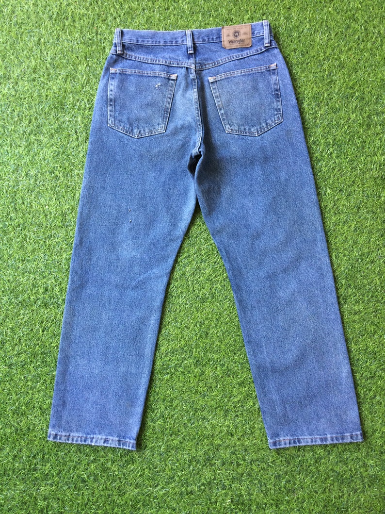May include: A pair of blue denim jeans with a brown leather patch on the back pocket that says "Wrangler".