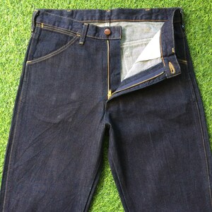 Peut inclure: Un jean en denim bleu fonc&eacute; avec une fermeture &eacute;clair et un bouton. Le jean a une coupe droite classique et est fait d'un denim lourd et durable.