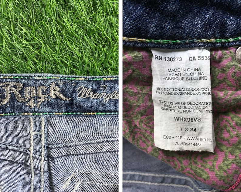 Op de afbeelding: Blauwe denim jeans met een Rock & Wrangler logo op de tailleband. De jeans heeft een bloemenprint op de achterzakken en een label met de tekst "RN 130273 CA 5539 Made in China Hecho en China Fabrique au Chine 99% Cotton/Algodon/Coto 1% Spandex/Spandex/Spand Exclusive of Decoration Excepto Decoracion/ Garniture Non Compris WHX96VS 7 X 34 EC2-11F-WWWH89113 760609414461".