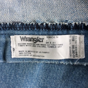 May include: A blue denim label with white text that reads "Wrangler 936DEN 36 X 31" and "MACHINE WASH HOT AND INSIDE OUT FIRST THREE TIMES WITH LIKE COLORS, TUMBLE DRY MADE IN MEXICO OF US FABRIC 100% COTTON EXCLUSIVE OF DECORATION".