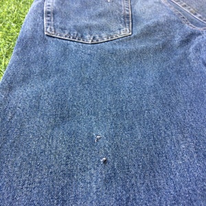 May include: A pair of blue denim jeans with a back pocket and a small hole in the fabric.