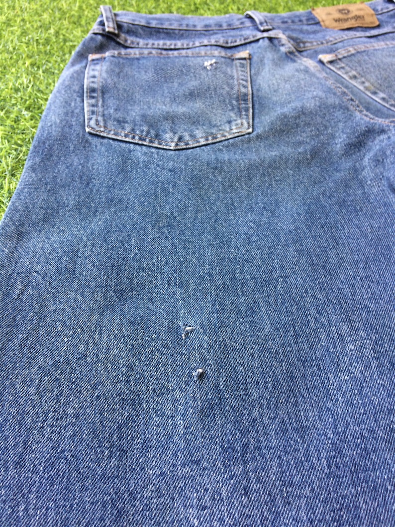 May include: A pair of blue denim jeans with a back pocket and a small hole in the fabric.