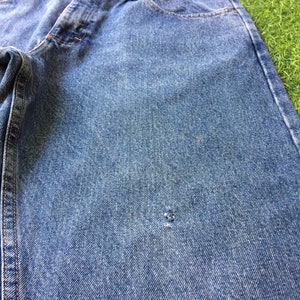 May include: A pair of blue denim jeans with a small hole in the fabric.