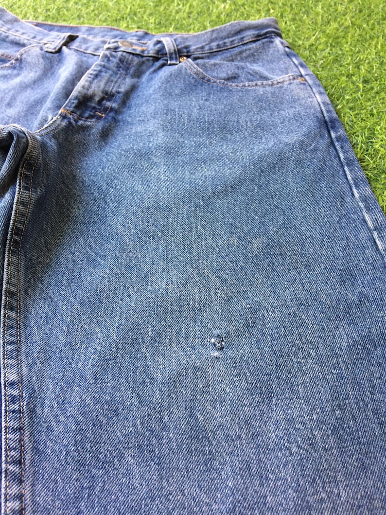 May include: A pair of blue denim jeans with a small hole in the fabric.
