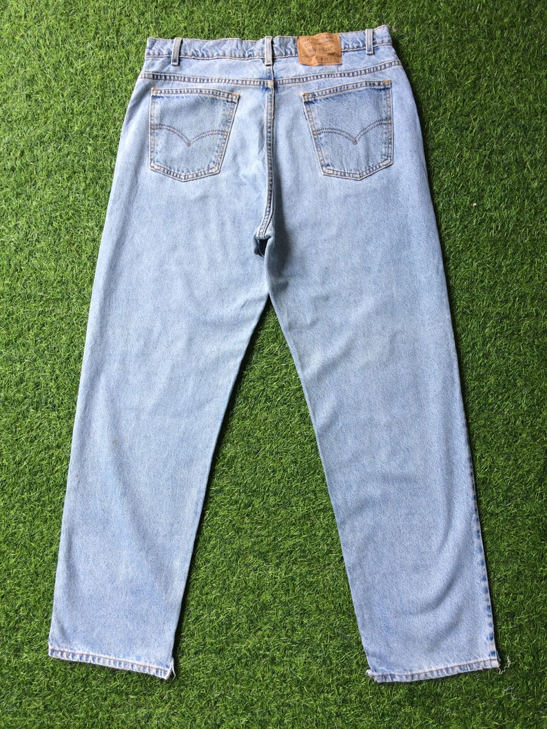 May include: A pair of light blue denim jeans with a brown leather patch on the back waistband. The jeans have a classic five-pocket style and a straight leg.