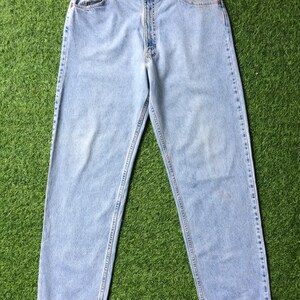 May include: Light blue denim jeans with a straight leg fit. The jeans have a classic five-pocket design and a button fly.