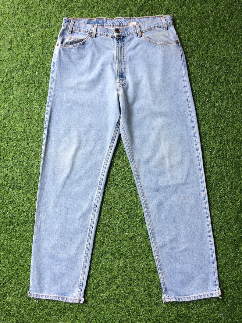 May include: Light blue denim jeans with a straight leg fit. The jeans have a classic five-pocket design and a button fly.