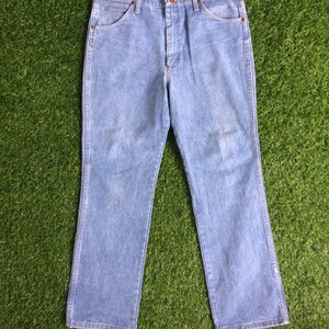 May include: A pair of light blue denim jeans with a straight leg fit. The jeans have a button fly and five pockets.