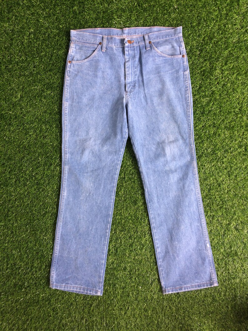 May include: A pair of light blue denim jeans with a straight leg fit. The jeans have a button fly and five pockets.