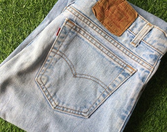 Może przedstawiać: Jasne niebieskie dżinsy z brązową skórzaną naszywką z napisem "Levi's" i "550" oraz rozmiarem "34 x 32".