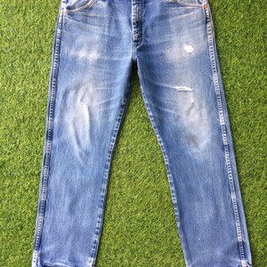 May include: A pair of blue denim jeans with distressed details and a straight leg fit.