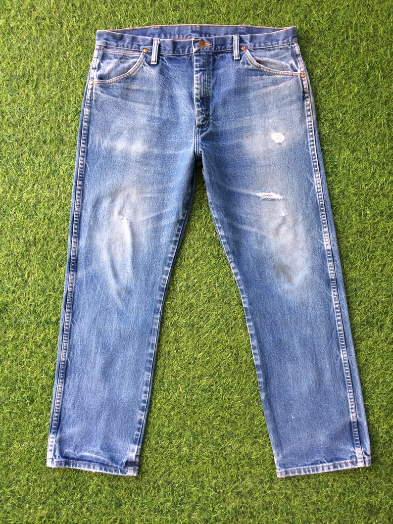 May include: A pair of blue denim jeans with distressed details and a straight leg fit.