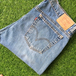 May include: A pair of blue denim jeans with a back pocket and a Levi's label. The label reads "Levi Strauss & Co.  San Francisco, CA.  Original  Levi's  Quality  Clothing  Since 1873".