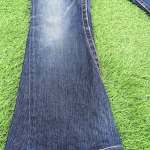 May include: A white ceramic mug with a black handle and the text "But First, Coffee" in a black, handwritten-style font. The mug is on a white surface.