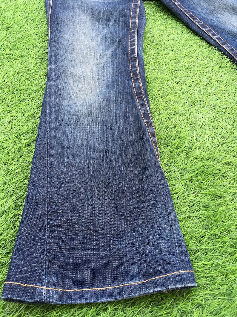 May include: A white ceramic mug with a black handle and the text "But First, Coffee" in a black, handwritten-style font. The mug is on a white surface.