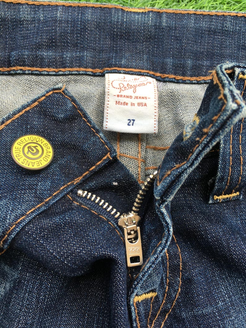 May include: A white ceramic mug with a black handle and the text "But First, Coffee" in a black, handwritten-style font. The mug is on a white surface.